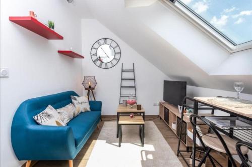 a living room with a blue couch and a clock at Appartement Cosy Amiens in Amiens