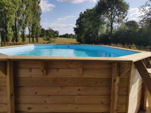 - une piscine dans un bâtiment en bois avec une terrasse en bois dans l'établissement Maison de la Grange, Chaulieu, à Sourdeval