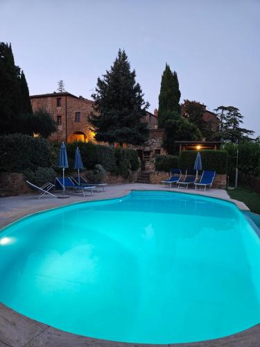 a large blue swimming pool with chairs and umbrellas at Borgo La Grancia in Montisi