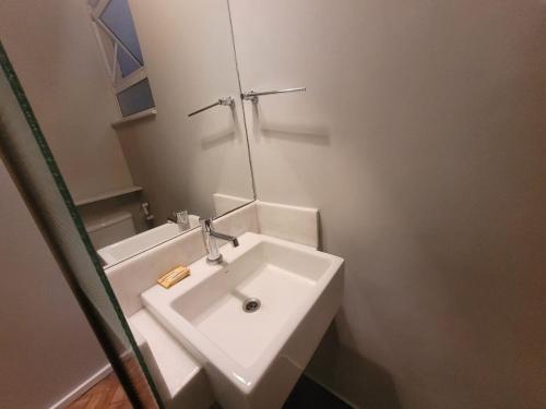 Baño blanco con lavabo y espejo en Suhcasa Leme Studio Confort en Río de Janeiro