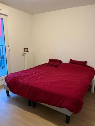 - un grand lit rouge dans une chambre blanche dans l'établissement Spacious apartment with big terrace - close to Paris, à Villeneuve-la-Garenne