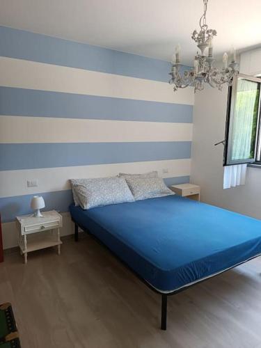 ein blaues Bett in einem Zimmer mit gestreifter Wand in der Unterkunft appartamento immerso nel verde tra laghi e colline in Anzano del Parco
