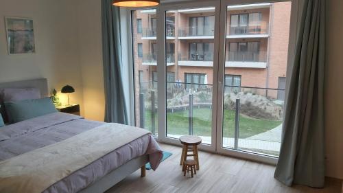 ein Schlafzimmer mit einem Bett und einem großen Fenster in der Unterkunft Courbevoie lodge in Louvain-la-Neuve