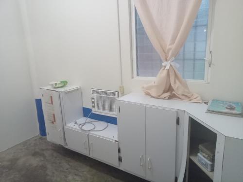 a room with white cabinets and a window at Hacienda Tropical Guest House in Belmopan
