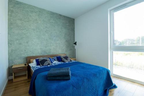 a bedroom with a blue bed and a large window at Lux Apartment in Rzeszów
