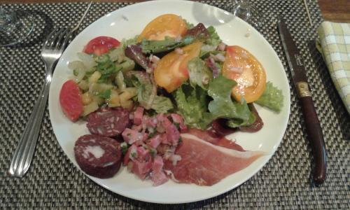 a plate of food with a salad on a table at Chambres d'Hôtes Le Bourdieu in Soulignac