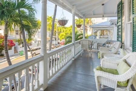 Un porche con sillas y mesas de mimbre y palmeras. en Curry House - Rooms 3 & 4, en Key West
