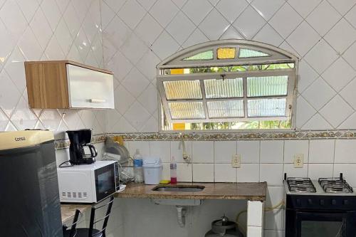 une cuisine avec un comptoir, un four micro-ondes et une fenêtre dans l'établissement Quarto/sala Região central, à Macaé