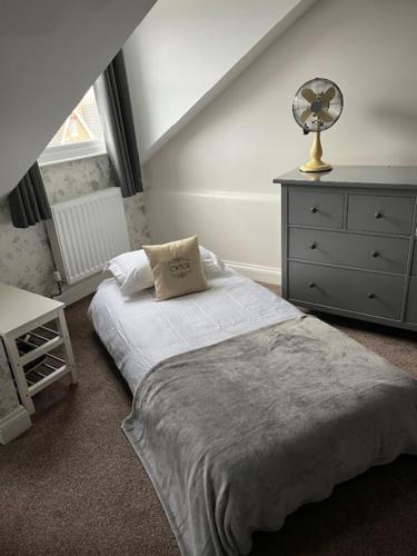 a bedroom with a bed with a fan and a dresser at Most Easterly - The Loft in Pakefield