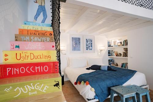 a bedroom with a stack of books next to a bed at Conversas de Alpendre in Vila Nova de Cacela