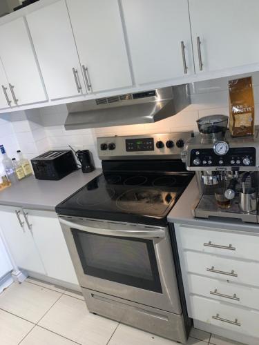 a kitchen with a stainless steel stove and white cabinets at Appartement 2 Chambre neuf in Longueuil