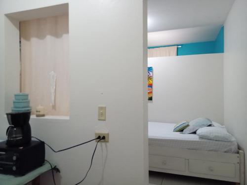 a small bedroom with a bed in a white room at Hacienda Tropical Guest House in Belmopan