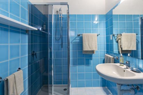 y baño de azulejos azules con lavabo y ducha. en Hotel Sole Mare, en Baja Sardinia