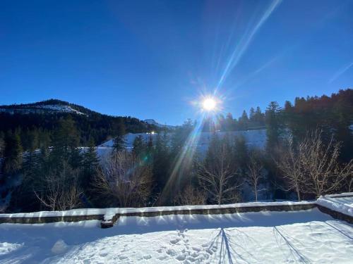 a winter view of the sun shining over a snow covered field at Appartement résidence le bec de l’aigle in Laveissière