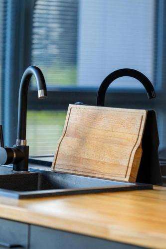 a kitchen sink with a wooden cutting board next to it at Lux Apartment in Rzeszów