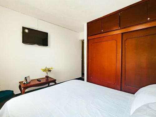 a bedroom with a bed with a wooden headboard and a table at Lindo apto amoblado ¡super central! RNT734 in Armenia