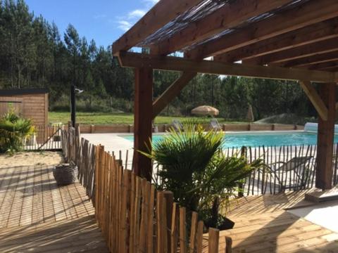 une clôture en bois en face d'une piscine dans l'établissement Chalet 2 chambres en Bois dans les landes n34, à Tosse