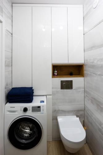 a bathroom with a washing machine and a toilet at Apartament Sunny Five in Suwałki