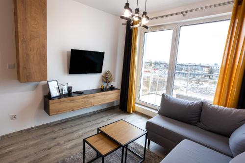 a living room with a couch and a large window at Apartament Sunny Five in Suwałki