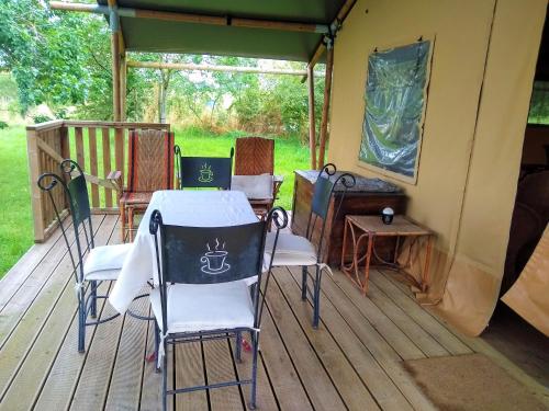 une table et des chaises assises sur une terrasse en bois dans l'établissement Le Lodge de Loge & Broc, à La Possonnière