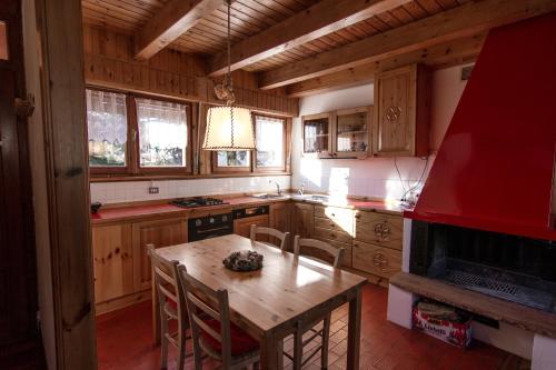 uma cozinha com uma mesa de madeira com cadeiras e um aparelho vermelho em App Carolina em Creazzo