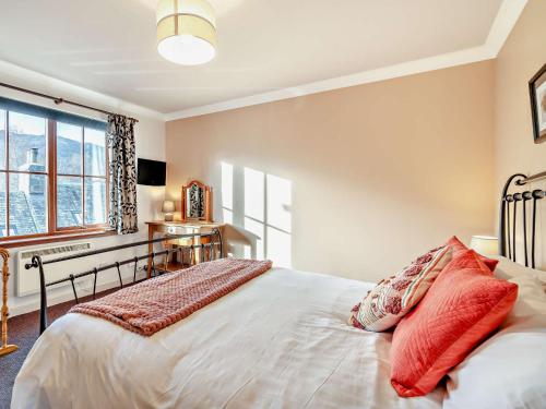 um quarto com uma cama com almofadas vermelhas em 1 Bed in Callander 45288 em Saint Fillans