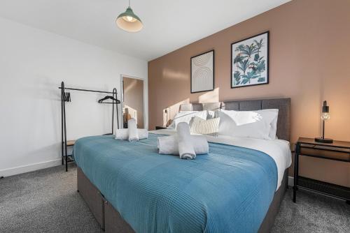 a bedroom with a large bed with a blue blanket at Stylish 4-Bedroom Townhouse with two large parking spaces and superfast Wi-Fi in Gloucester