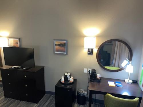 a hotel room with a desk and a mirror at Comfort Inn & Suites in Toledo