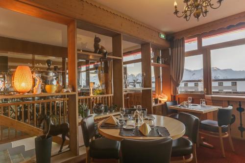 a restaurant with a table and chairs and windows at Le Castillan in L'Alpe-d'Huez