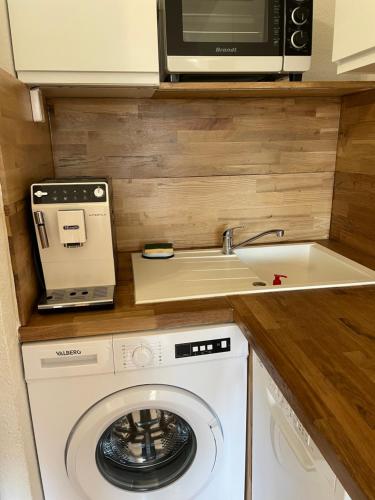 a kitchen with a washing machine and a microwave at Studio cabine barcares in Le Barcarès