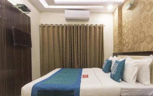 a bedroom with a bed with blue and white pillows at New Accore Inn Plus By Glitz Hotels in Mumbai