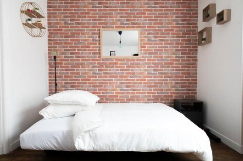 - une chambre avec un mur en briques et un lit avec des oreillers dans l'établissement The Nice Place proche Paris et Disney, à Neuilly-sur-Marne
