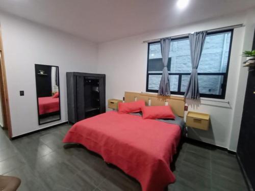 Schlafzimmer mit einem roten Bett und einem großen Fenster in der Unterkunft Suite Departamento Nuevo in Aguascalientes