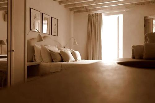 una camera bianca con un letto e una finestra di La Maison Kalogera a Mykonos Città