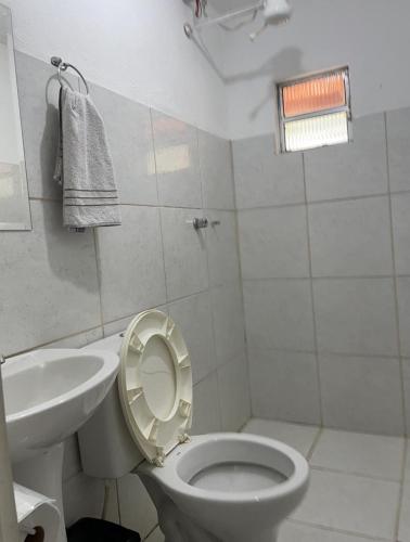a white bathroom with a toilet and a sink at Hotel Boa Vista in Matipó