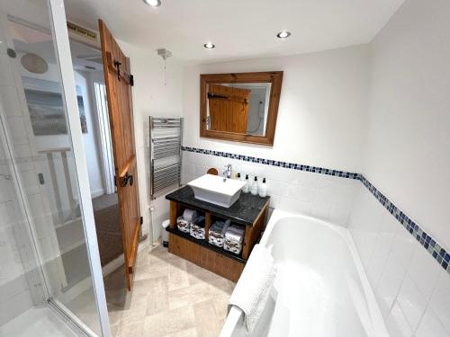 a bathroom with a tub and a sink and a mirror at Angel Cottage in Bishopsteignton