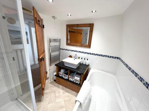 een badkamer met een bad, een wastafel en een spiegel bij Angel Cottage in Bishopsteignton