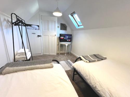 a room with two beds and a television in it at Angel Cottage in Bishopsteignton