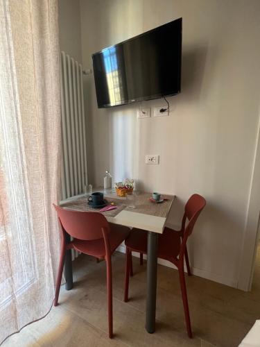 a table with two chairs and a television on a wall at Calari Rooms - Affittacamere in Bologna