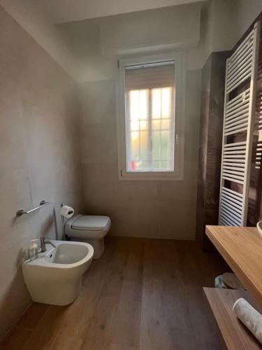 a bathroom with a toilet and a sink and a window at Calari Rooms - Affittacamere in Bologna