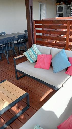 a white couch with colorful pillows on a deck at Le zami ola in Trois Bassins