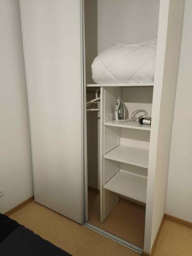 Cette chambre comprend un placard avec des étagères blanches et un lit. dans l'établissement Appartement T2 - PMR à 750 Mètres de la Station Thermale d'Avène (34), à Avène
