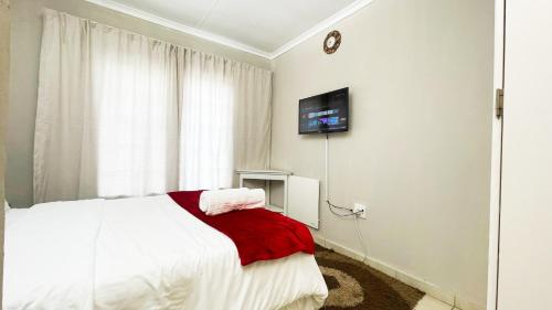 1 dormitorio con 1 cama y TV en la pared en Two Bedrooms at CASA MIA-Katode Street-in ANKAZIMIA HOUSE, en Roodepoort