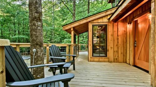 a wooden deck with two chairs and a house at The Poplar in Treehouse Grove at Norton Creek in Gatlinburg