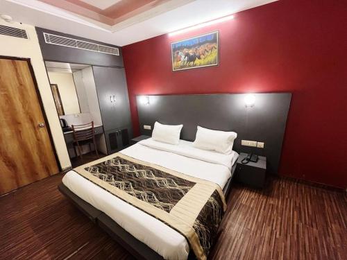 Hotel Diamond Airport في نيودلهي: غرفة نوم بسرير كبير وبجدار احمر
