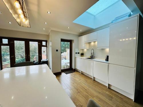 a kitchen with white cabinets and a large window at Spacious 6 Bed Residence in Wembly, London in London