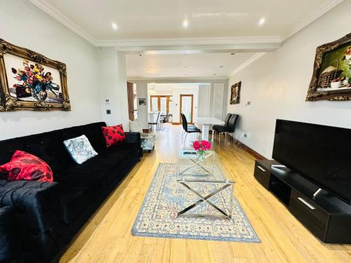 a living room with a black couch and a table at Spacious 6 Bed Residence in Wembly, London in London