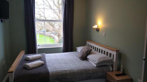 1 dormitorio con 1 cama con 2 almohadas y ventana en The Ashville Bed and Breakfast en Bristol