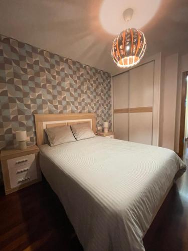 a bedroom with a large bed and a chandelier at APARTAMENTO CON EXCELENTES VISTAS AL MAR EN LA PLAYA DE CARNOTA in Caldebarcos