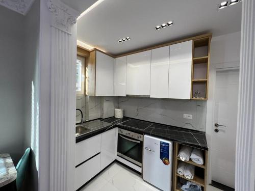 uma cozinha com armários brancos, um lavatório e uma máquina de lavar louça em Leti Apartments M.Shyri2 em Tirana